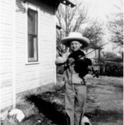 ca 1947. All hat 'n no cattle, but I had a dog. Do you reckon that dog liked my fiddlin'? If he did, he was the only one. My fiddlin' drove everybody else nuts. Mama used to say, 'Take that outside, Sonny boy.' Sonny playing fiddle as a kid